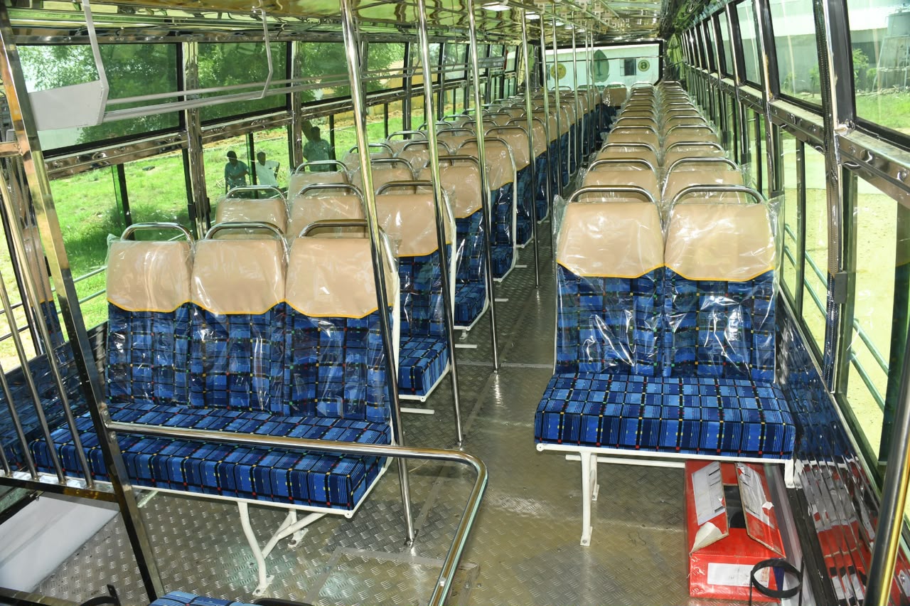 Blue institutional bus interior with stainless grab rails and cushioned bench seating, Karur